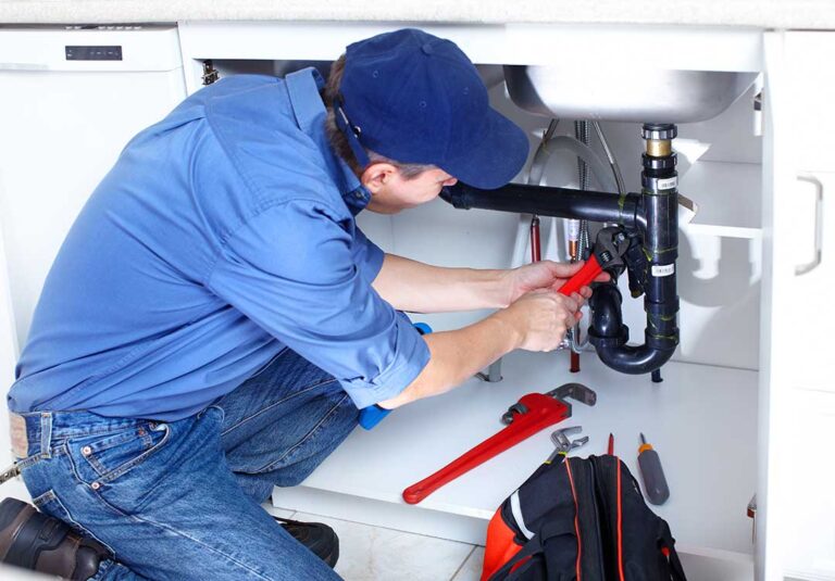 A homeowner checking a water meter in a residential basement to diagnose a possible plumbing leak.