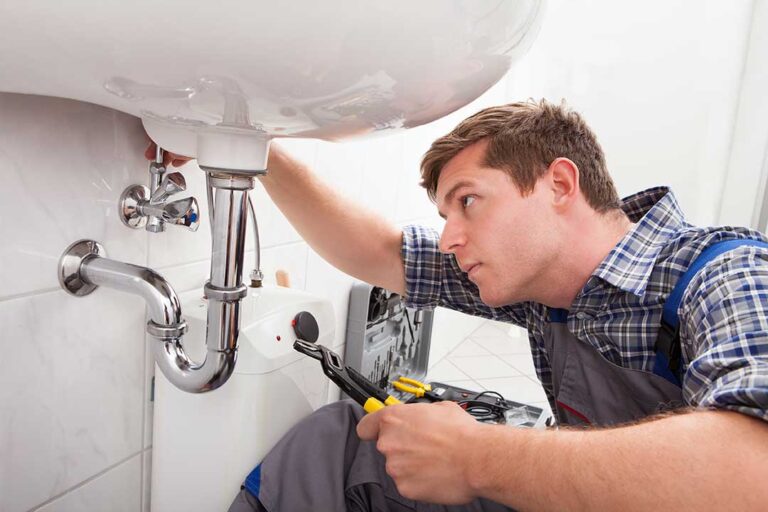 A person checking a home water meter with a notepad and pen in hand.